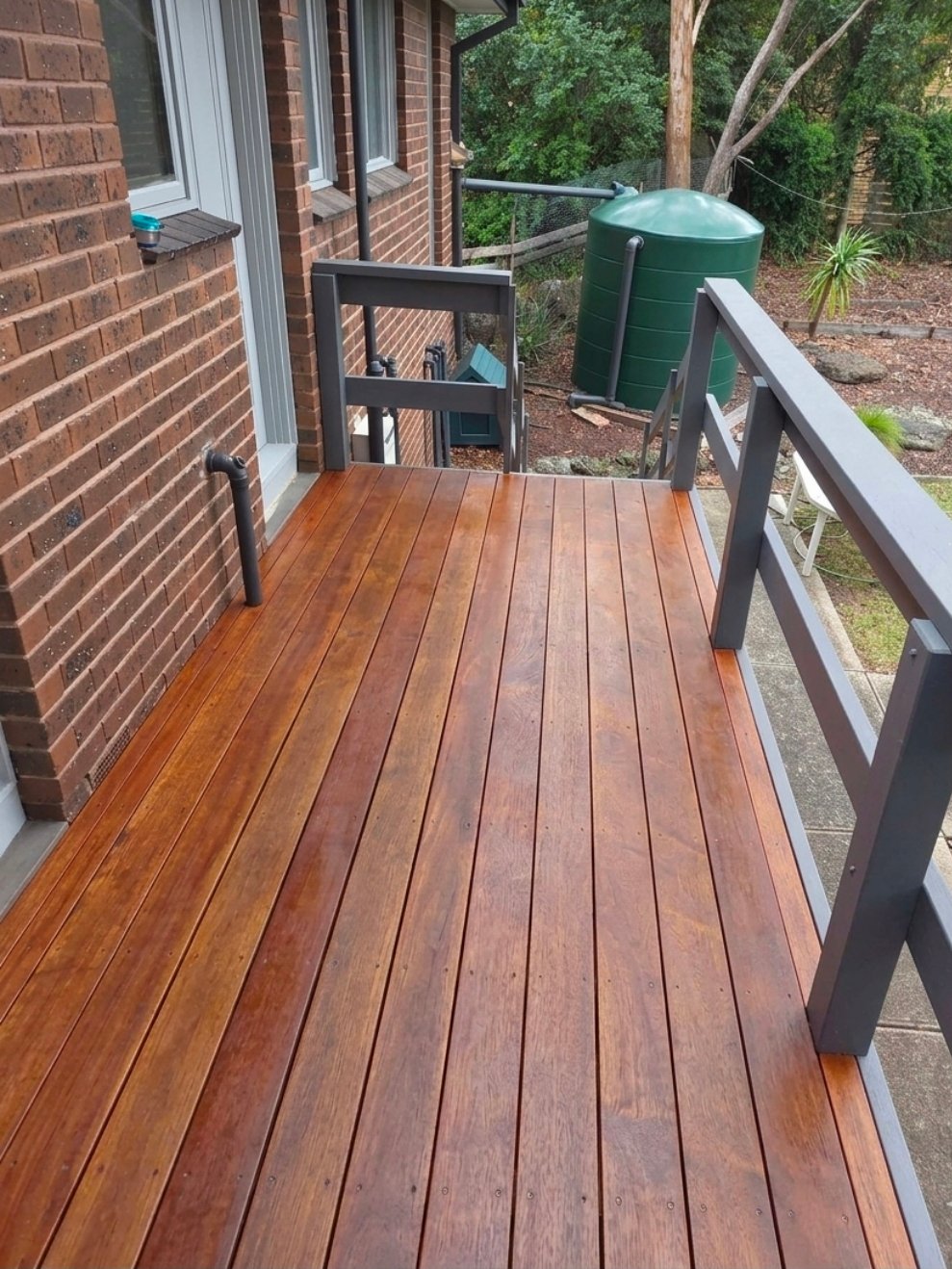 After decking makeover photo showing the same deck with a rich red-toned refreshed timber finish