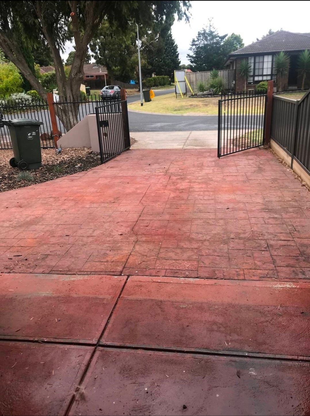 Before driveway refresh photo showing a red stamped concrete driveway finish