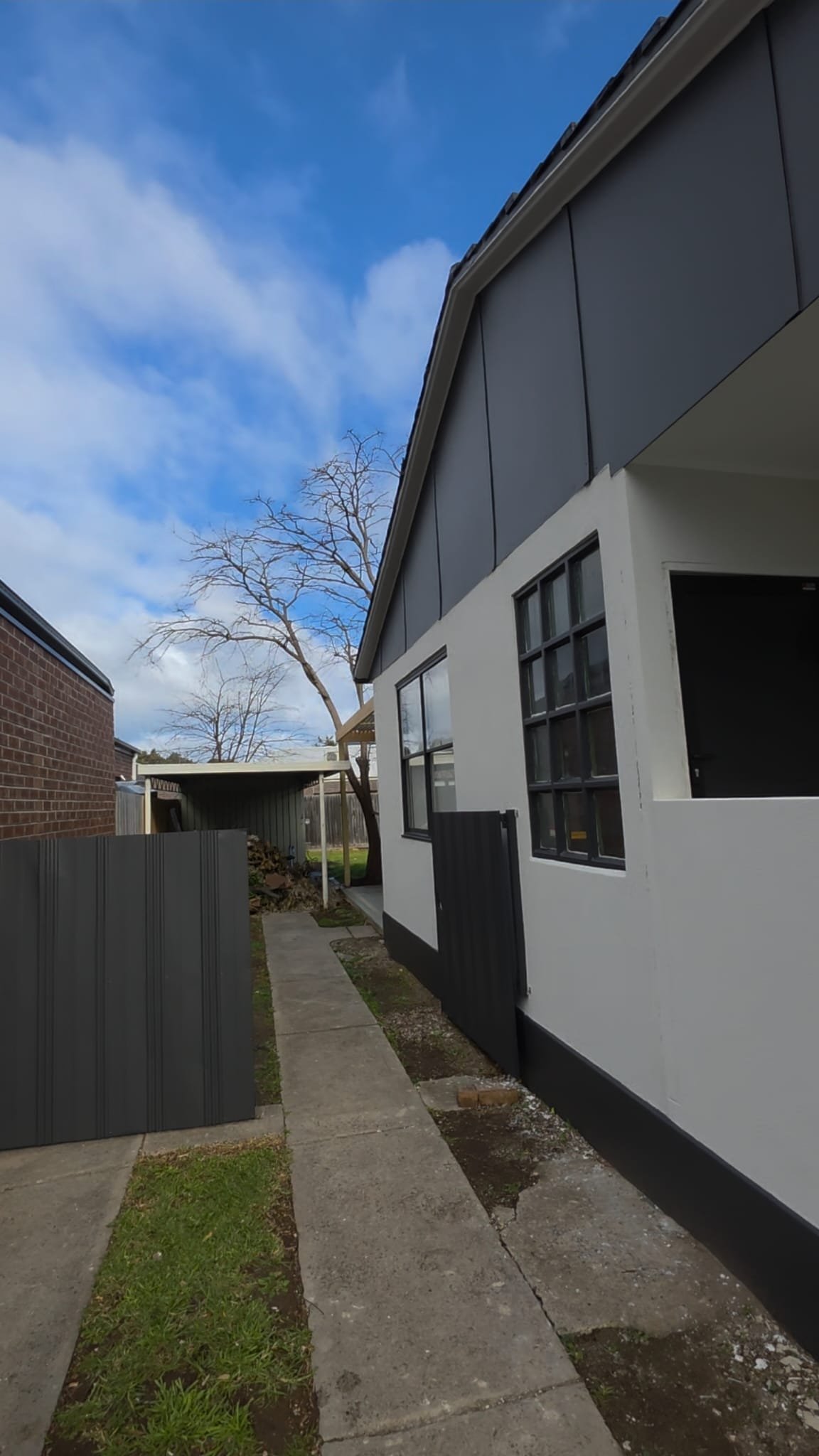 After exterior refresh photo showing the same side elevation repainted in crisp white with dark trim