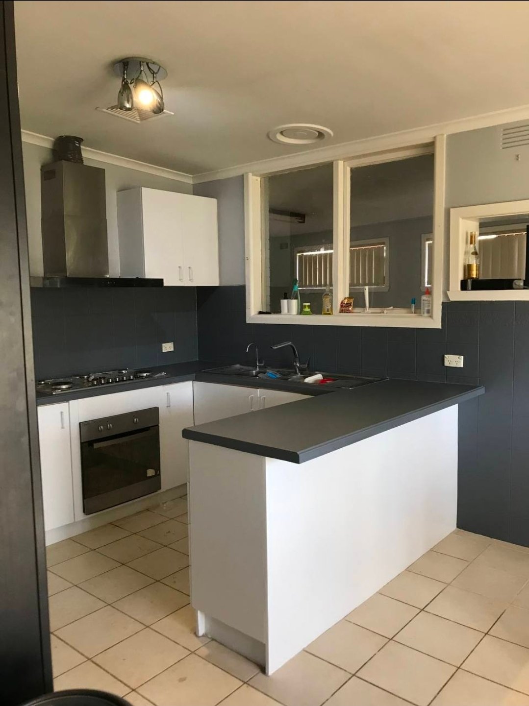 After kitchen refresh photo showing a cleaner white and charcoal repaint update to the same kitchen